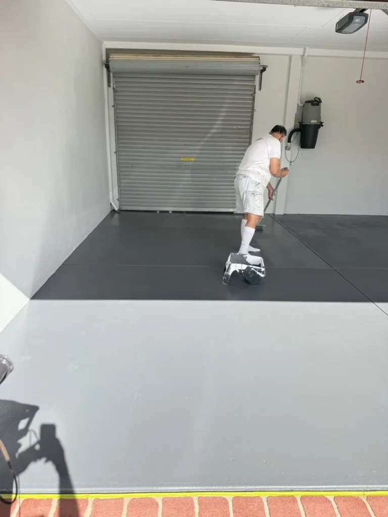 Painter cutting in the edge of a two-tone grey painted floor in Kardinya