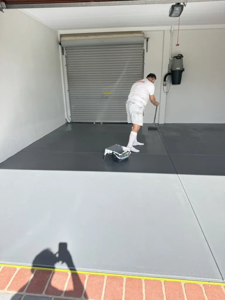 Painter rolling grey floor paint across a concrete floor in a Kardinya tenancy